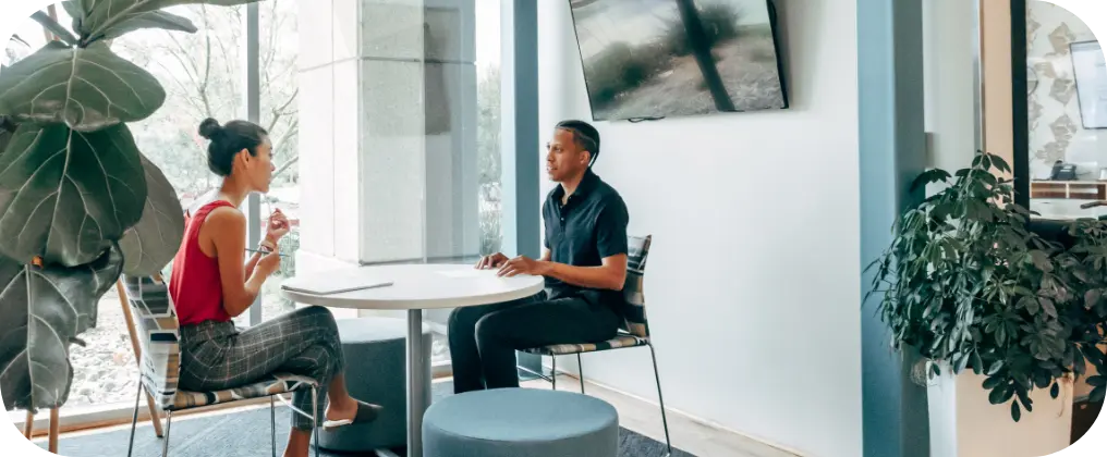 Two individuals engaged in an interview process, sitting at a table in an office.