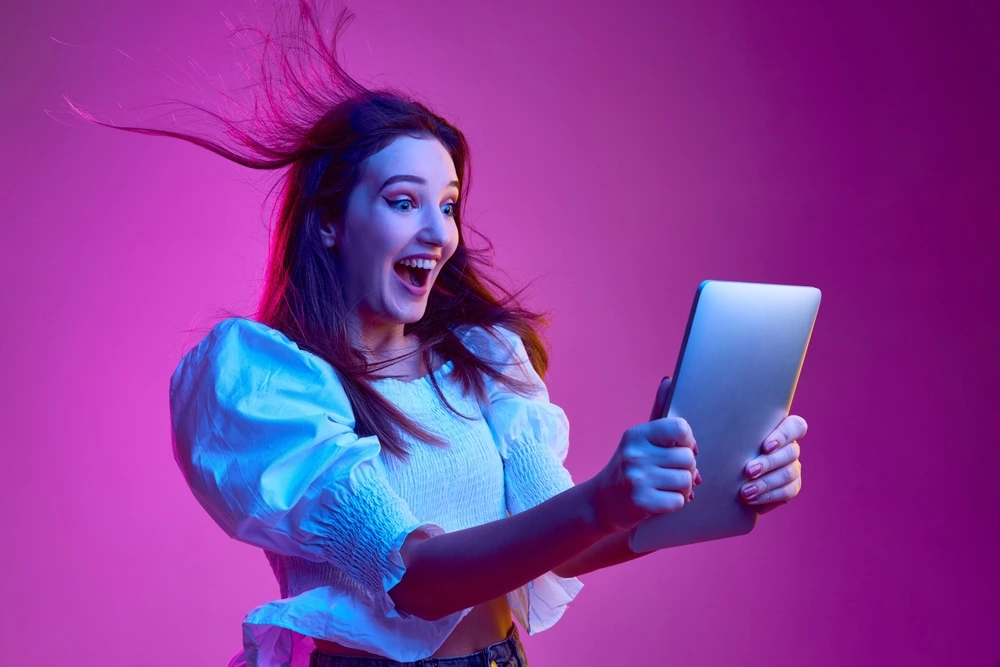 A woman holds a tablet, happy that she has got the job of her dreams.