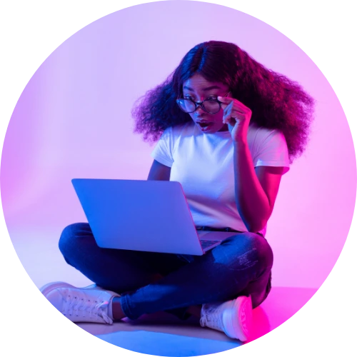 A woman sitting on the floor with a laptop, accessing MIH courses.